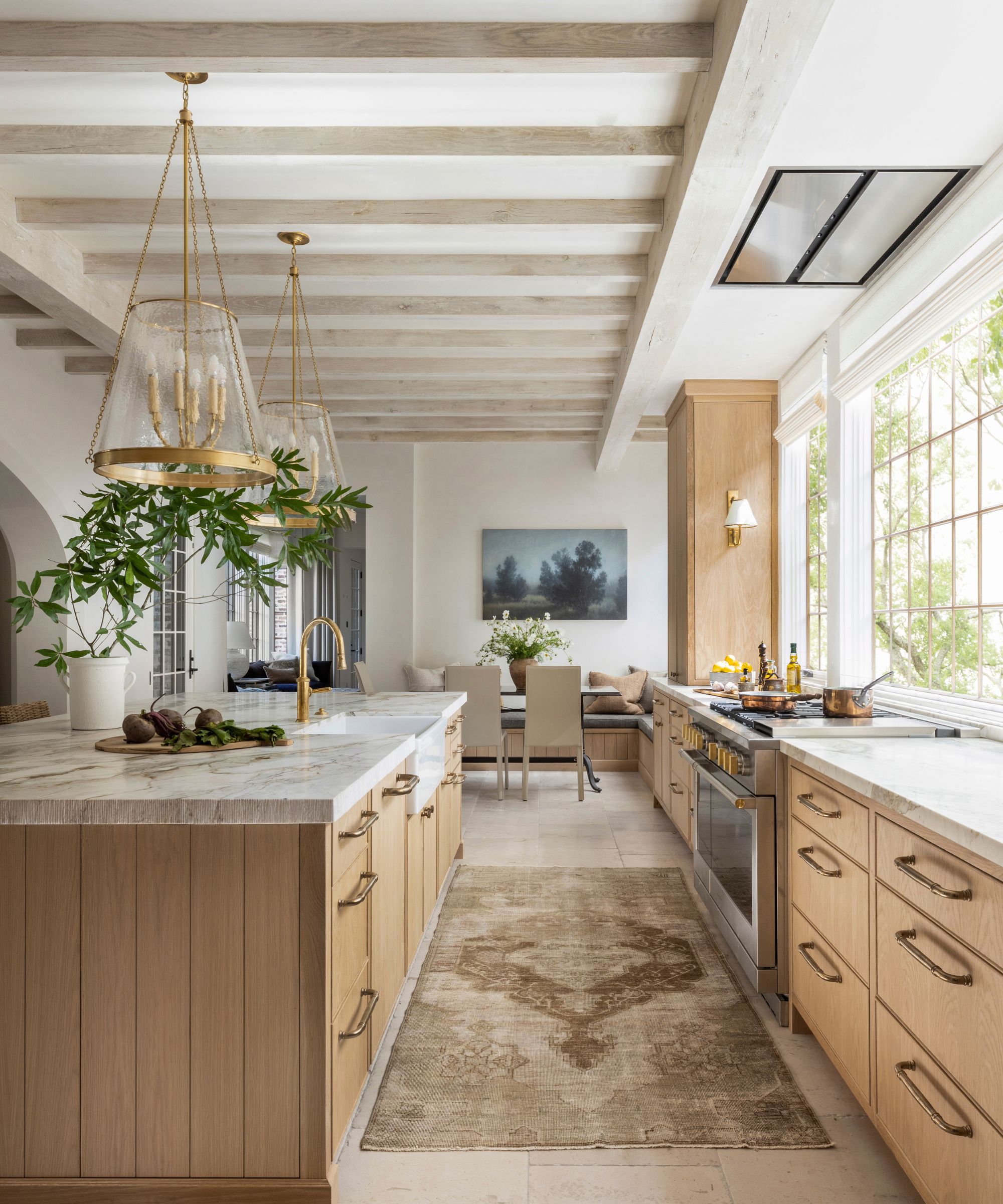 A modern wooden kitchen with a vintage runner on the floor, marble slabs and large brass pendant lights so that the program feels older