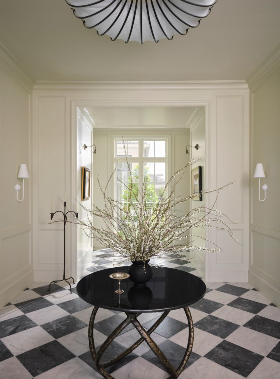 Elegant hallway with a checkered floor, round table and flower machine piece.