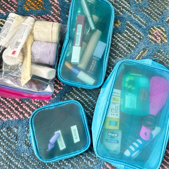 Three blue power bags with different toilet articles and a plastic -ziploc bag filled with toilet articles.