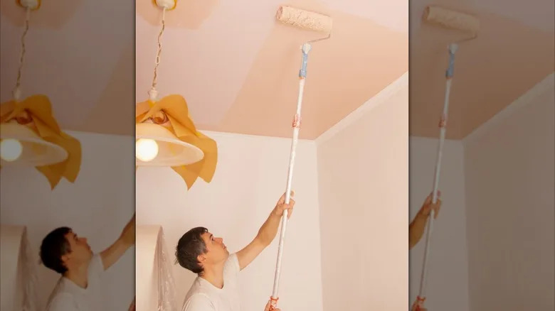 Man painting blanket a darker pink than the walls