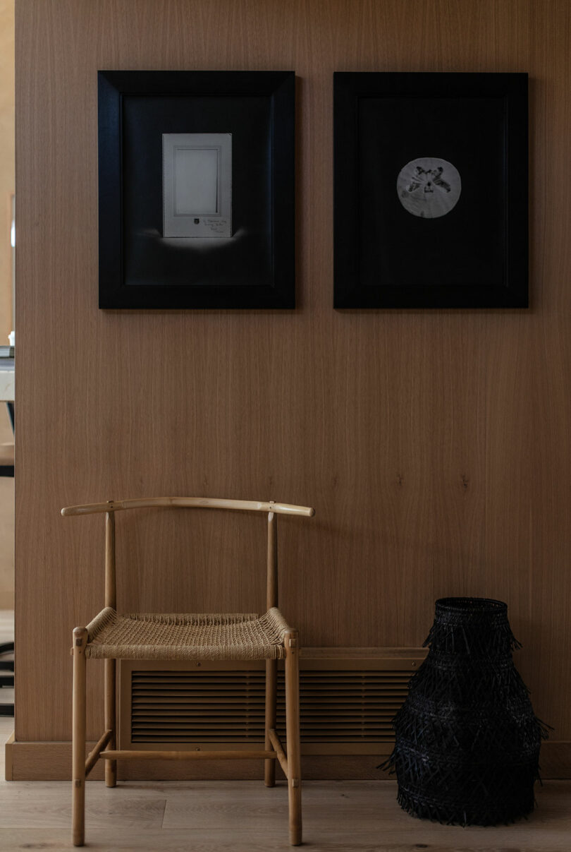 Curved white sofa with neutral pillow next to a round black coffee table with two high white candles that are used for sheer white curtains.