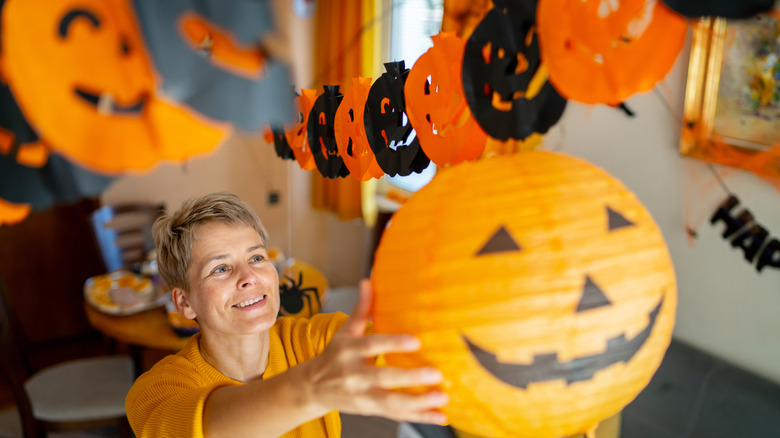 Smiling person hanging paper jacko lantern for party