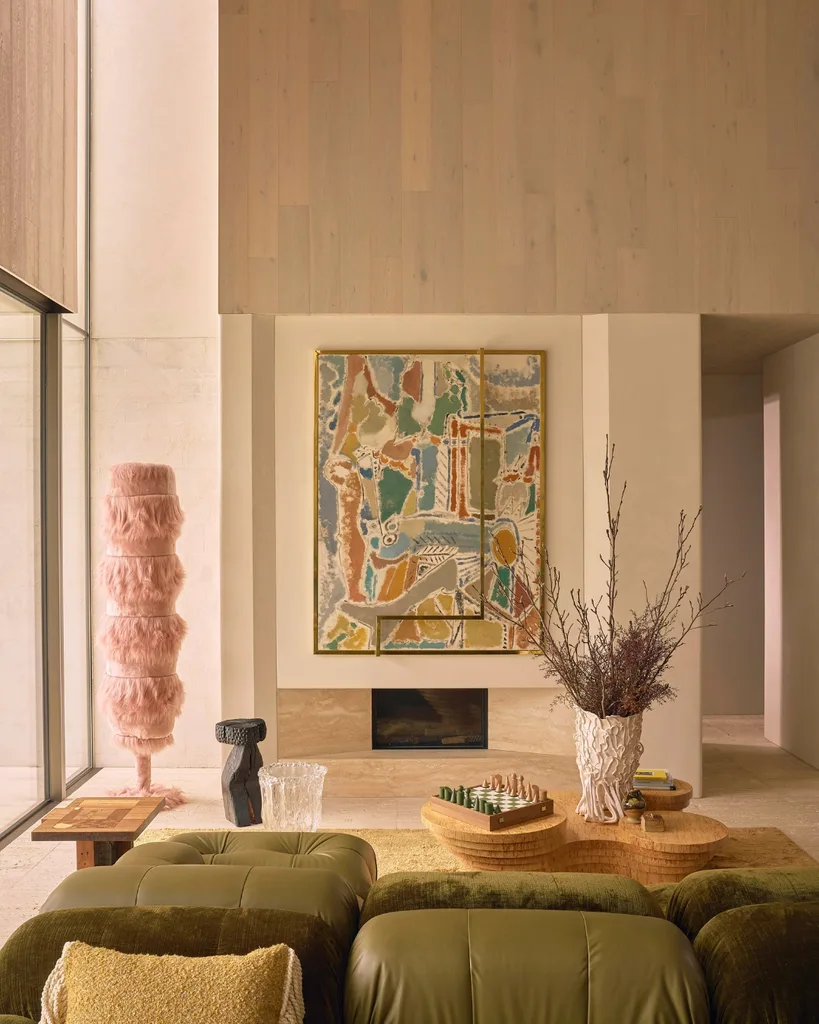 Modern living room with asymmetrical walls, green leather sofa, contemporary pastel works of art and marble fireplace.