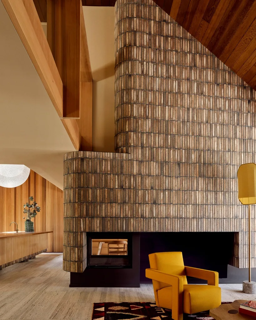 Modern interior with a large, structured brick fireplace, a yellow armchair and wood accents. 