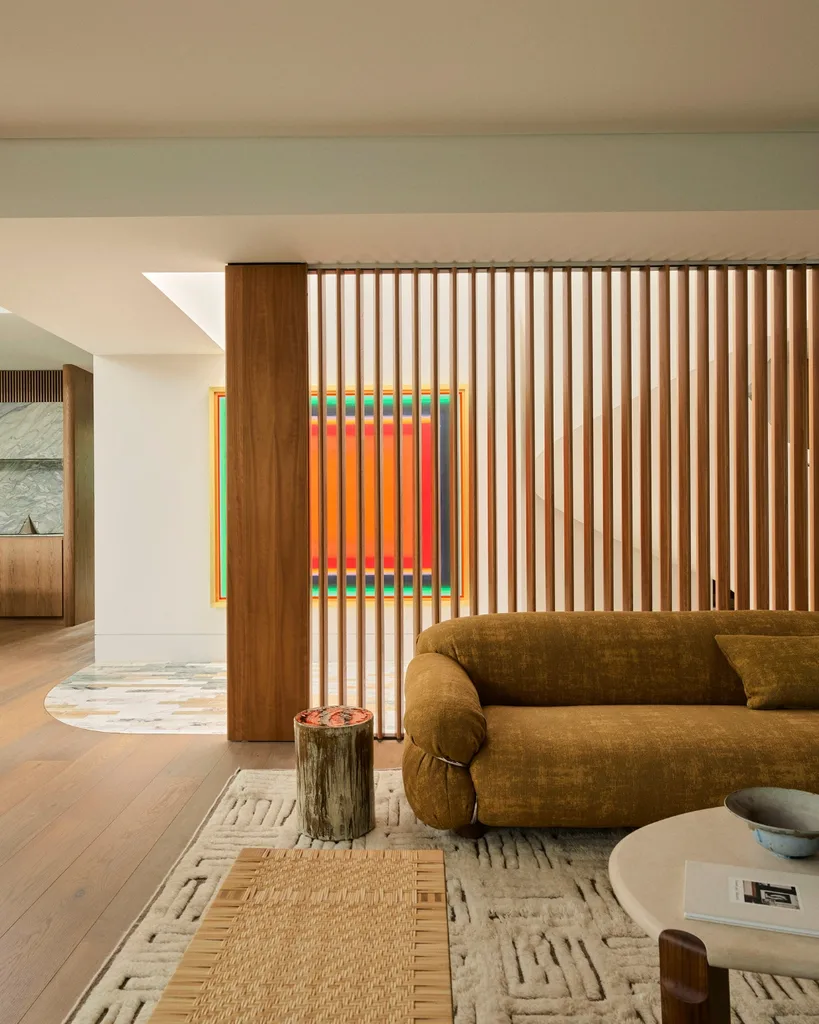 Modern living room with a structured brown sofa, wooden accents, abstract art and a round coffee table on a patterned carpet. 