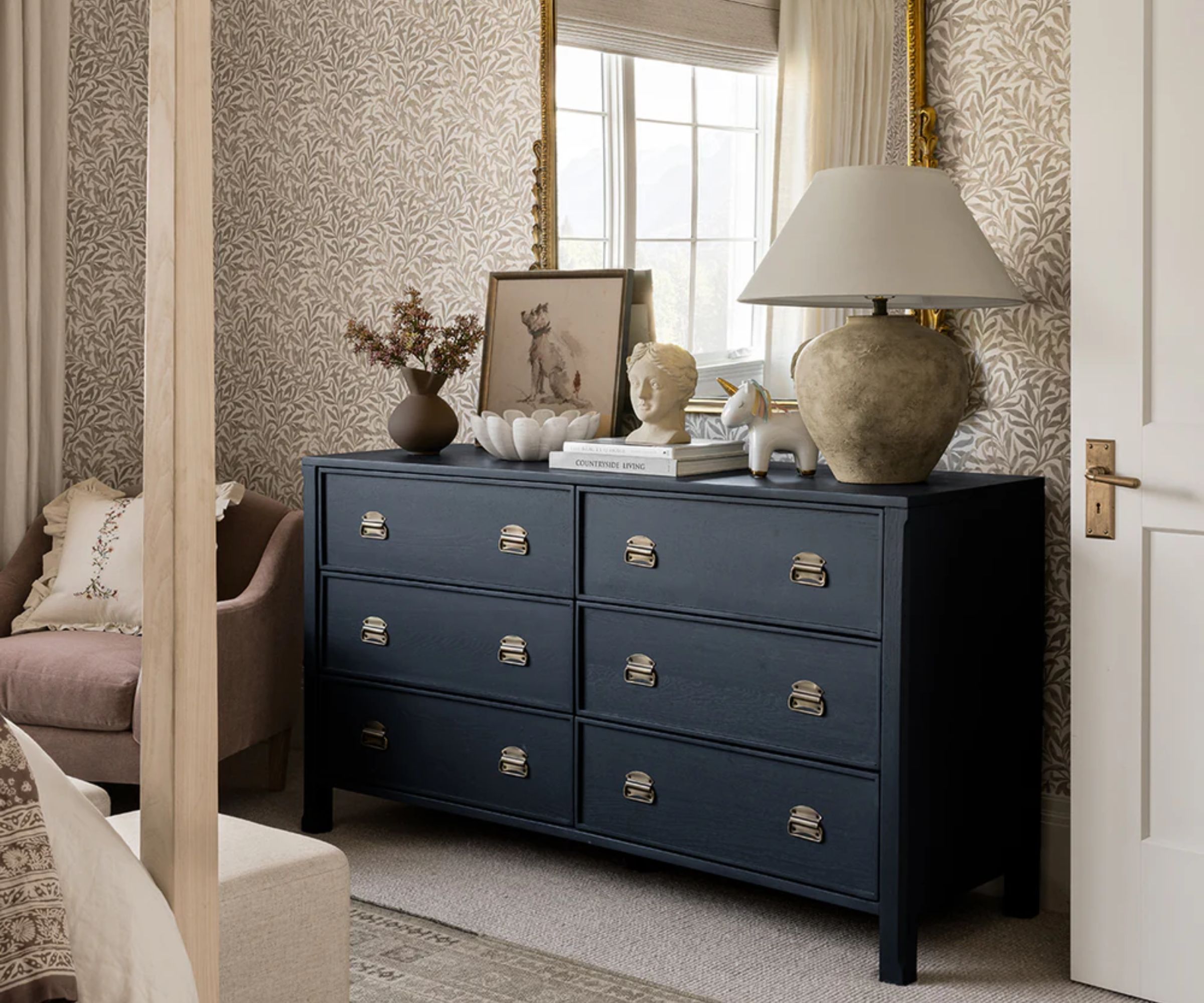 A dark blue painted chest of drawers with 6 drawers in a bedroom.