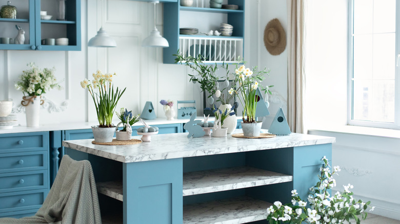 A cozy kitchen with blue cabinets and white marble countertops