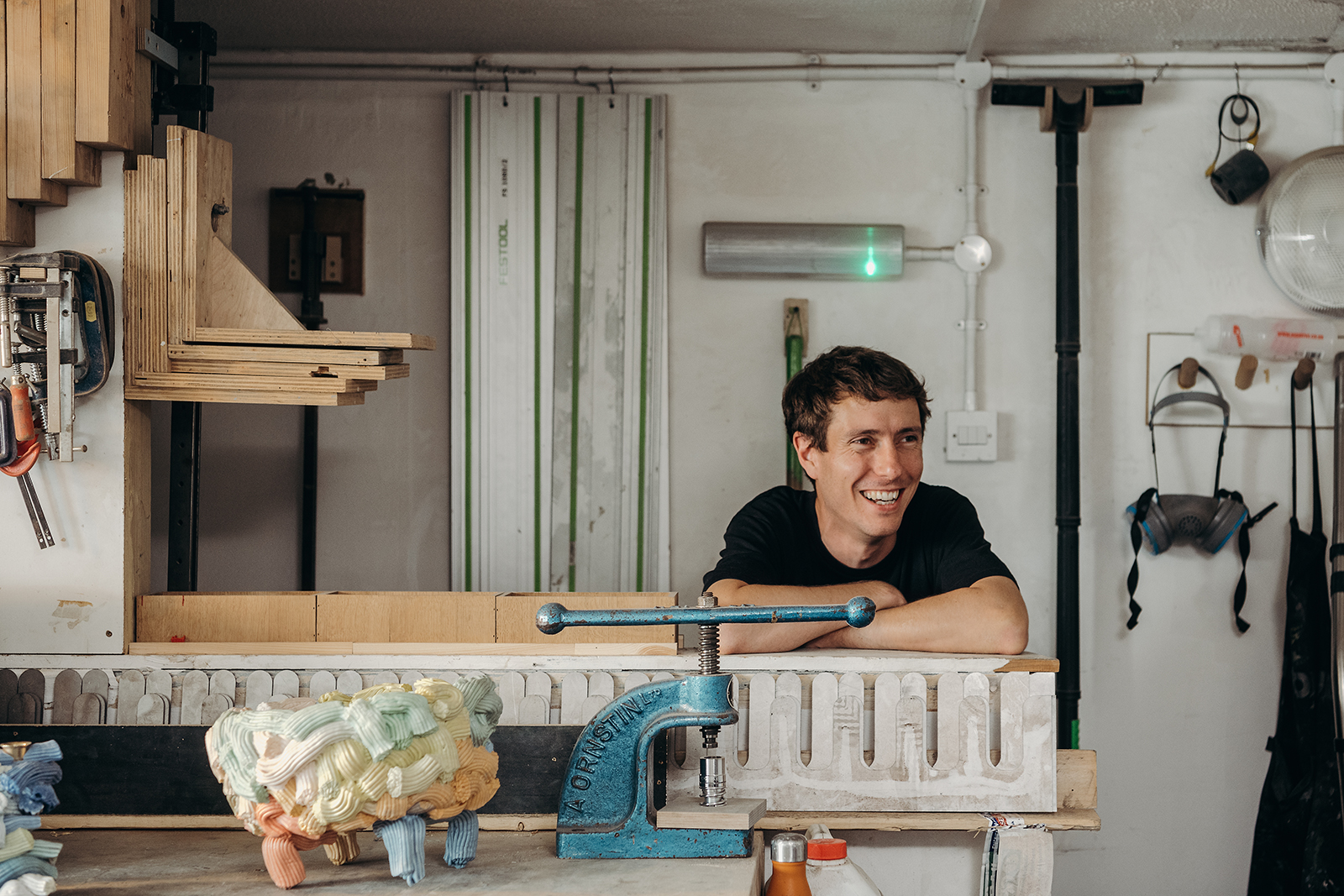 A young artisan was caught smiling in his workshop while wearing a black t-shirt.