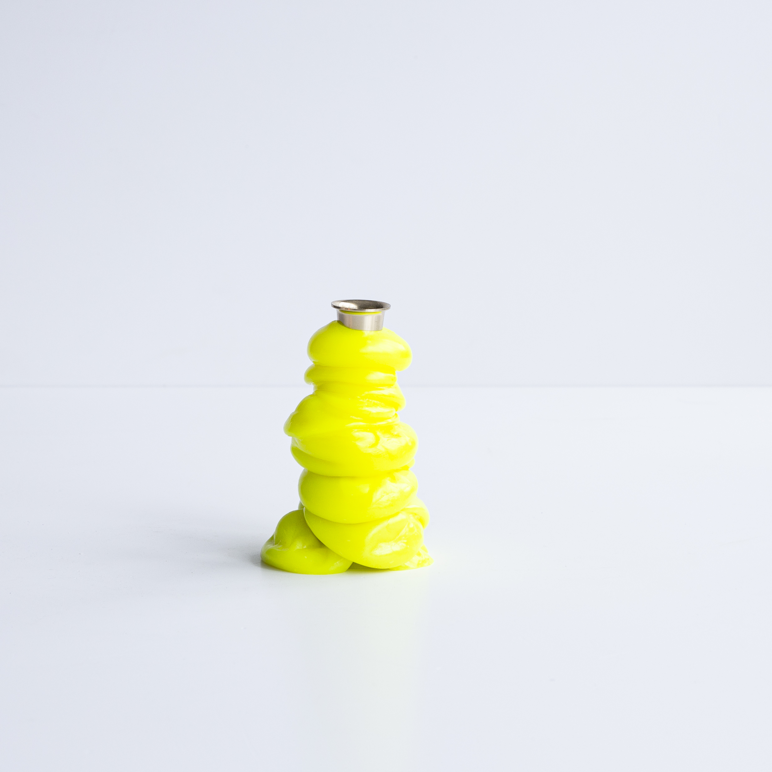 A range of soft home objects made from melted plastic and chrome or brass details, including a mirror, a candlestick and a kitchen towel holder.