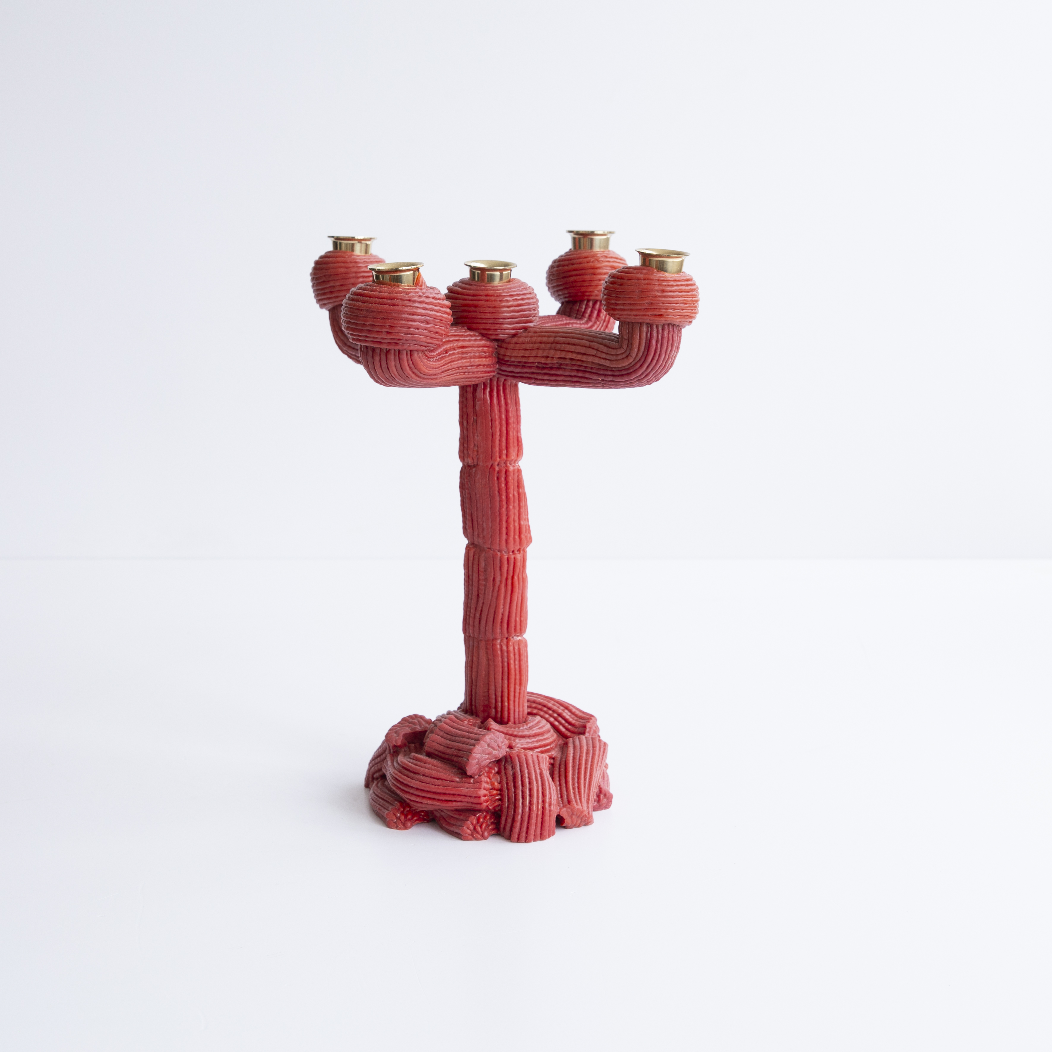 A range of soft home objects made from melted plastic and chrome or brass details, including a mirror, a candlestick and a kitchen towel holder.