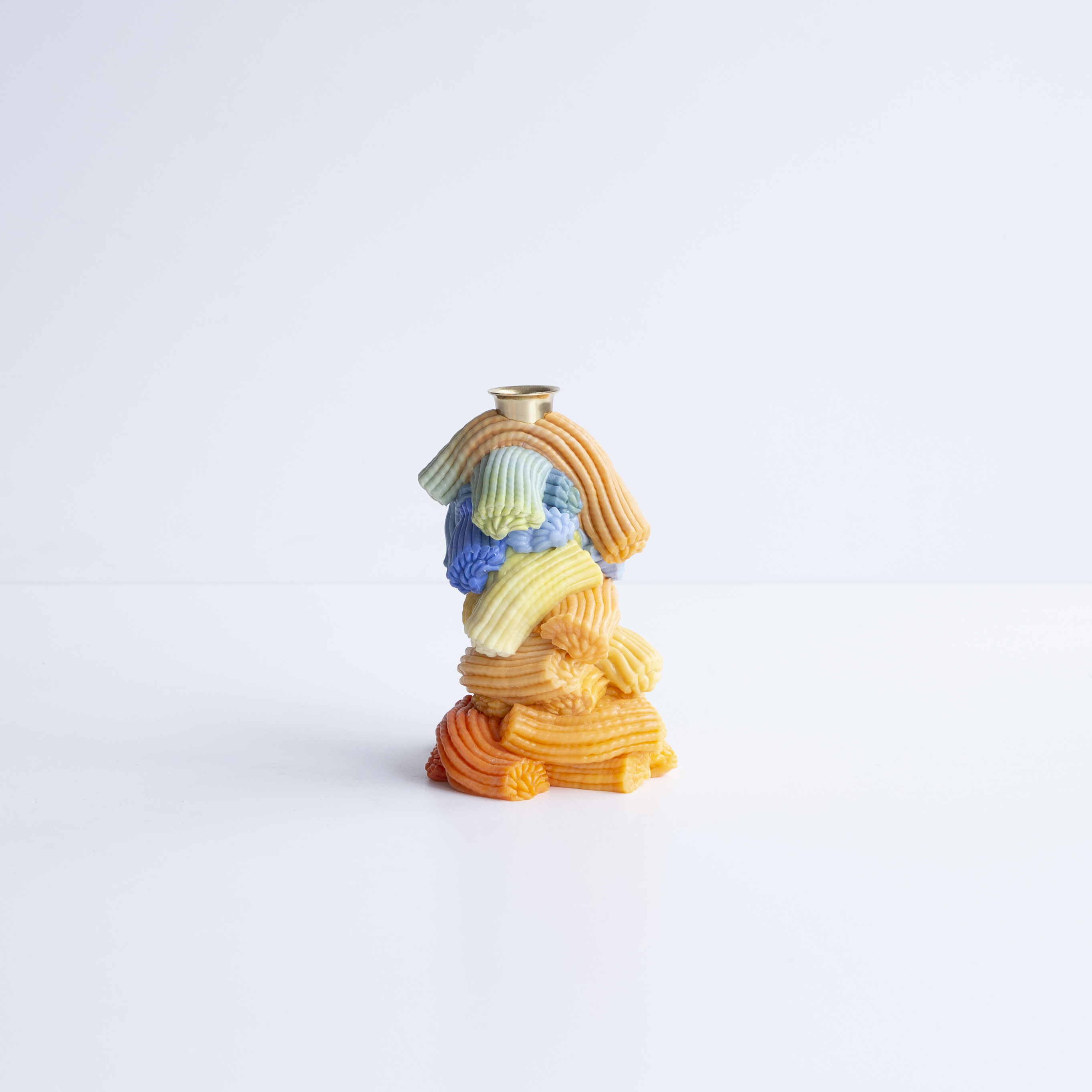 A range of soft home objects made from melted plastic and chrome or brass details, including a mirror, a candlestick and a kitchen towel holder.