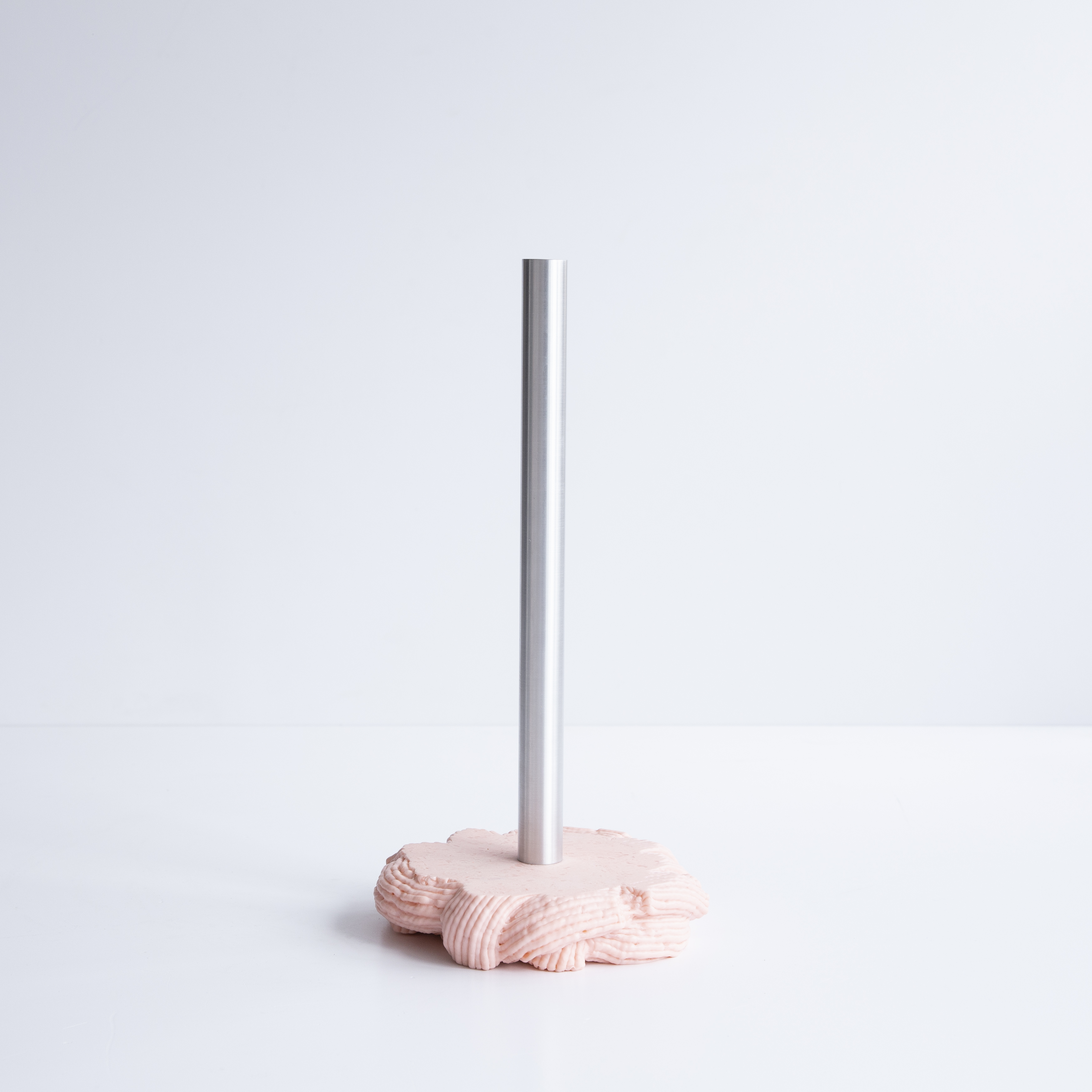 A range of soft home objects made from melted plastic and chrome or brass details, including a mirror, a candlestick and a kitchen towel holder.