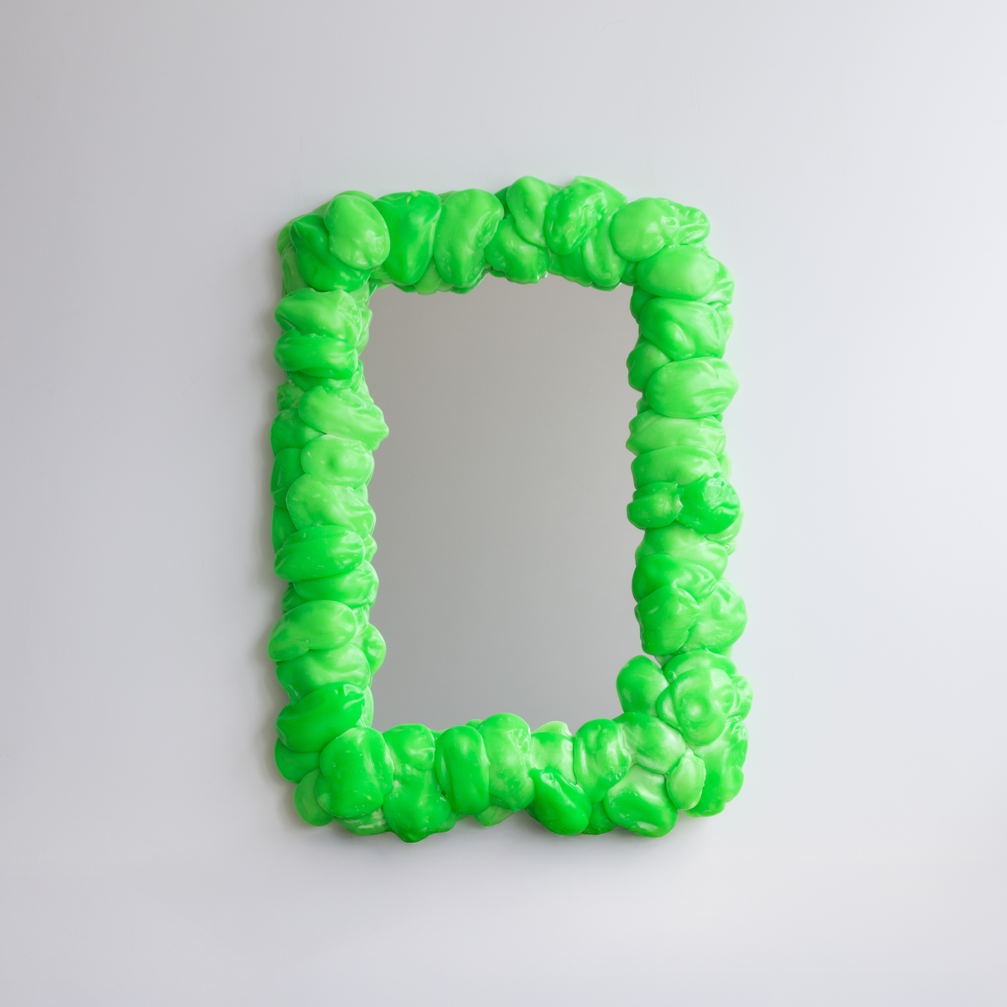 A range of soft home objects made from melted plastic and chrome or brass details, including a mirror, a candlestick and a kitchen towel holder.