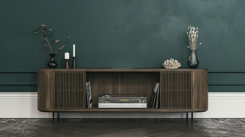 Dark wood media cabinet in front of a green wall