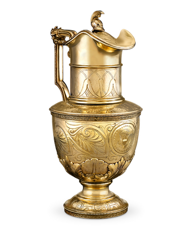 Ornate golden jug with intricate engravings and decorative handle against a plain background.
