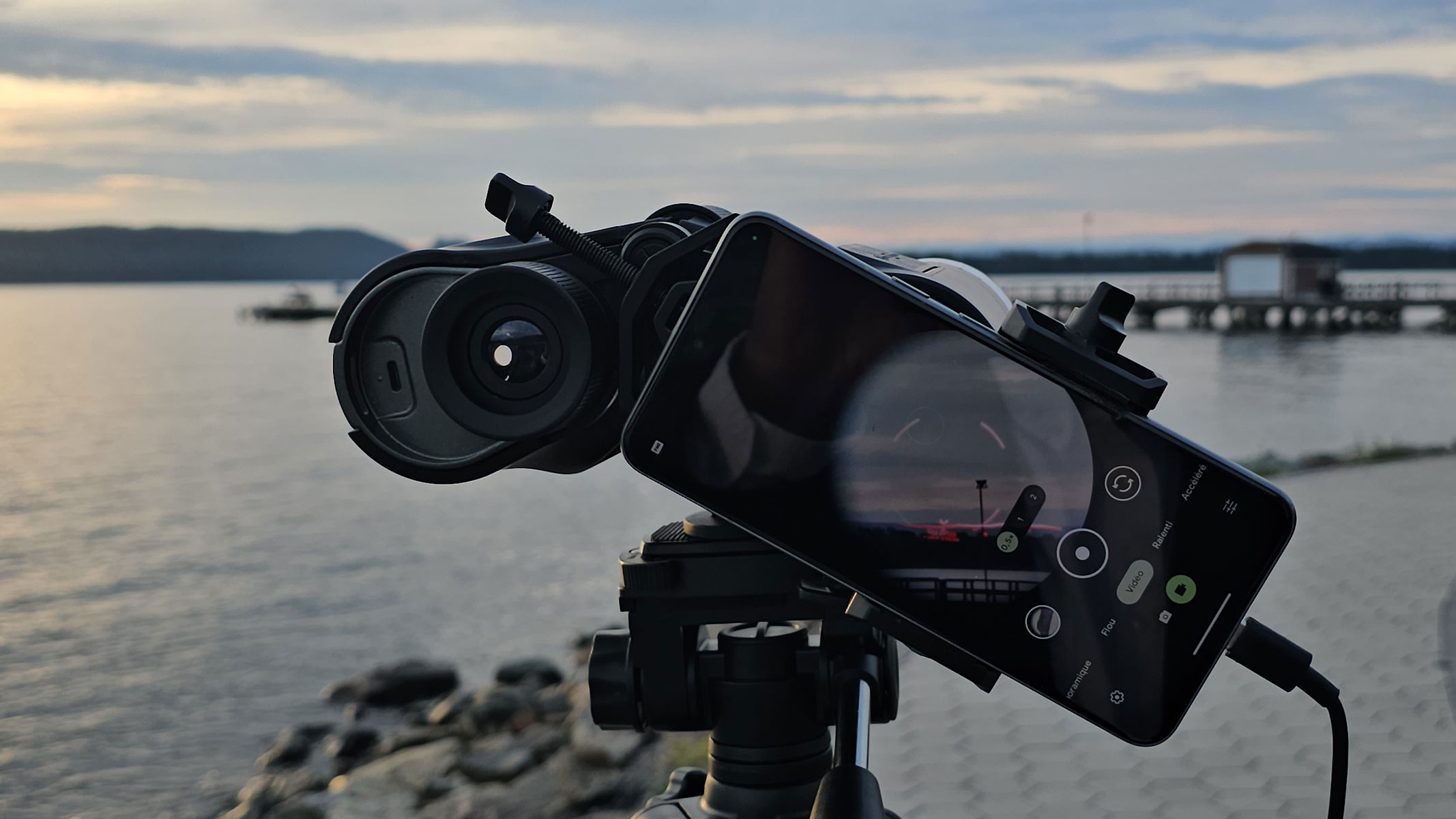 A smartphone showing the view through Unistellar Envision binoculars with a red AR overlay of the landscape with a lake in the background.