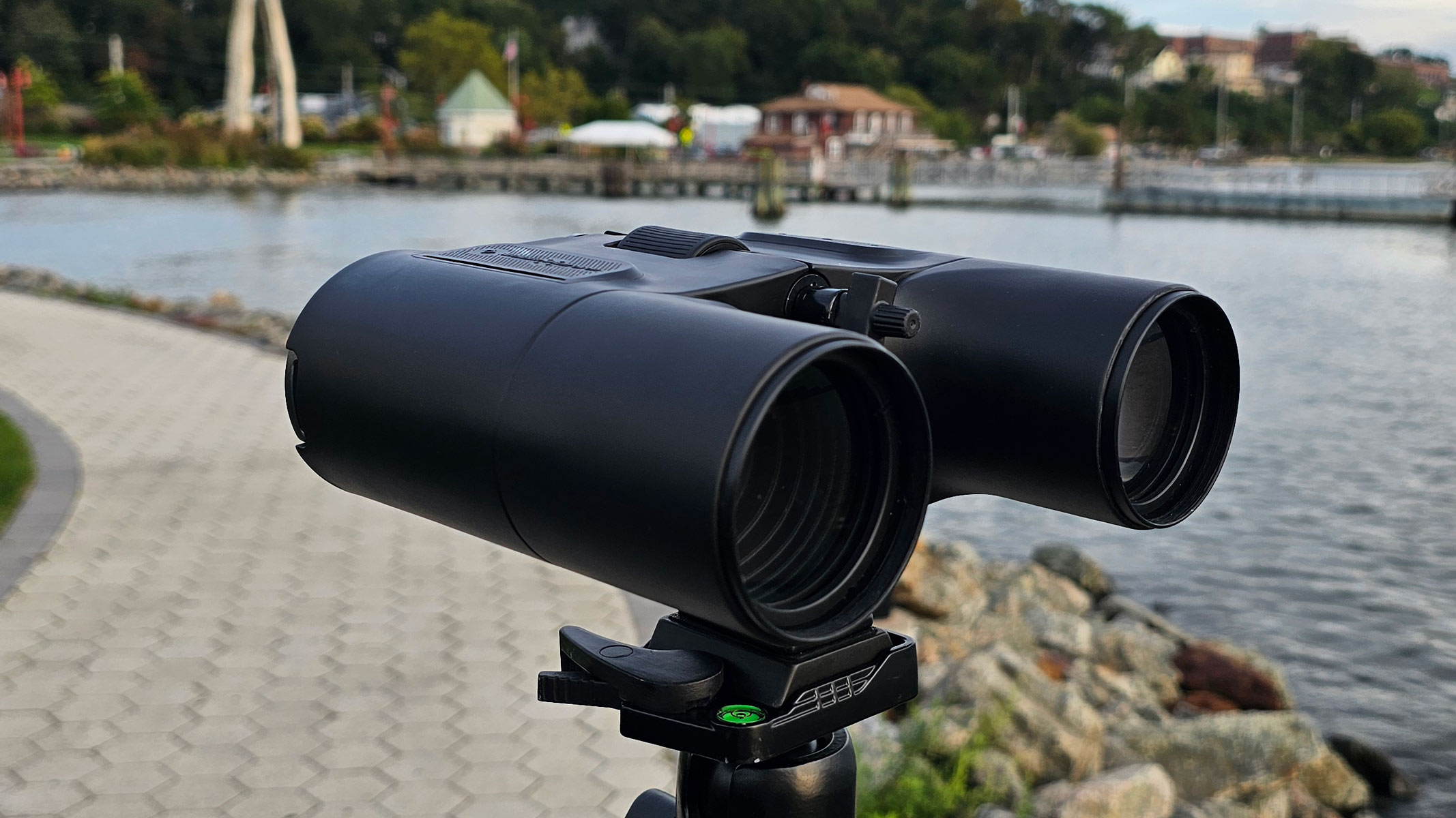 A side view of the Unistellar Envision smart binoculars with water and houses in the background.