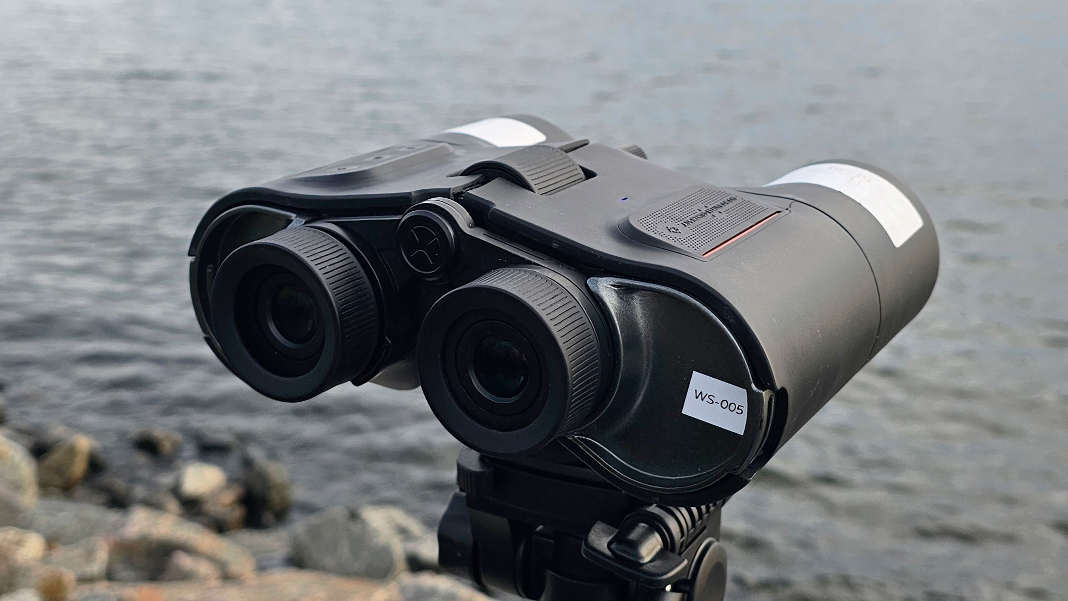 A rear view of the Unistellar Envision smart binoculars with water in the background.