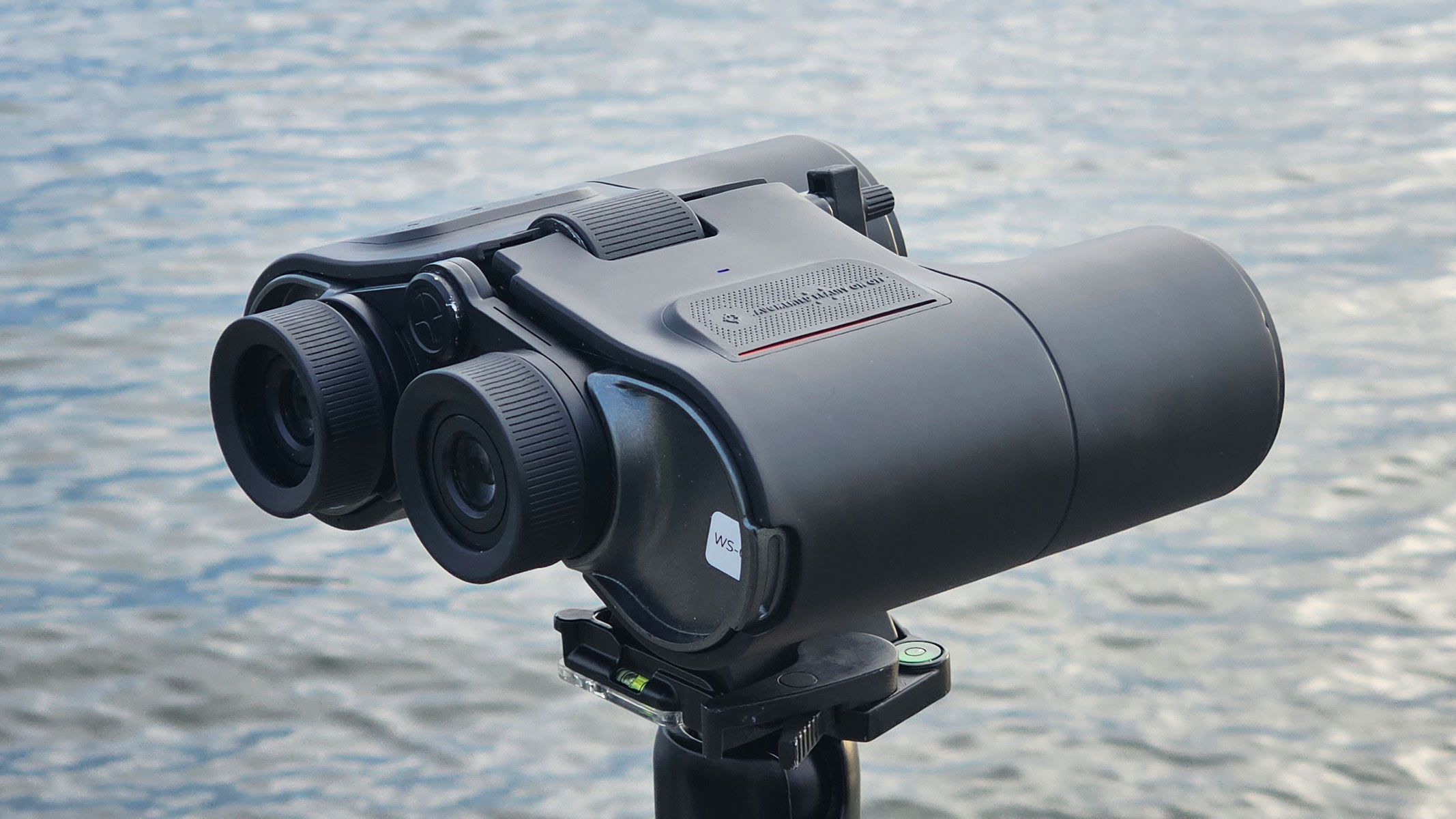 A side rear view of the Unistellar Envision Smart Binoculars with water in the background.