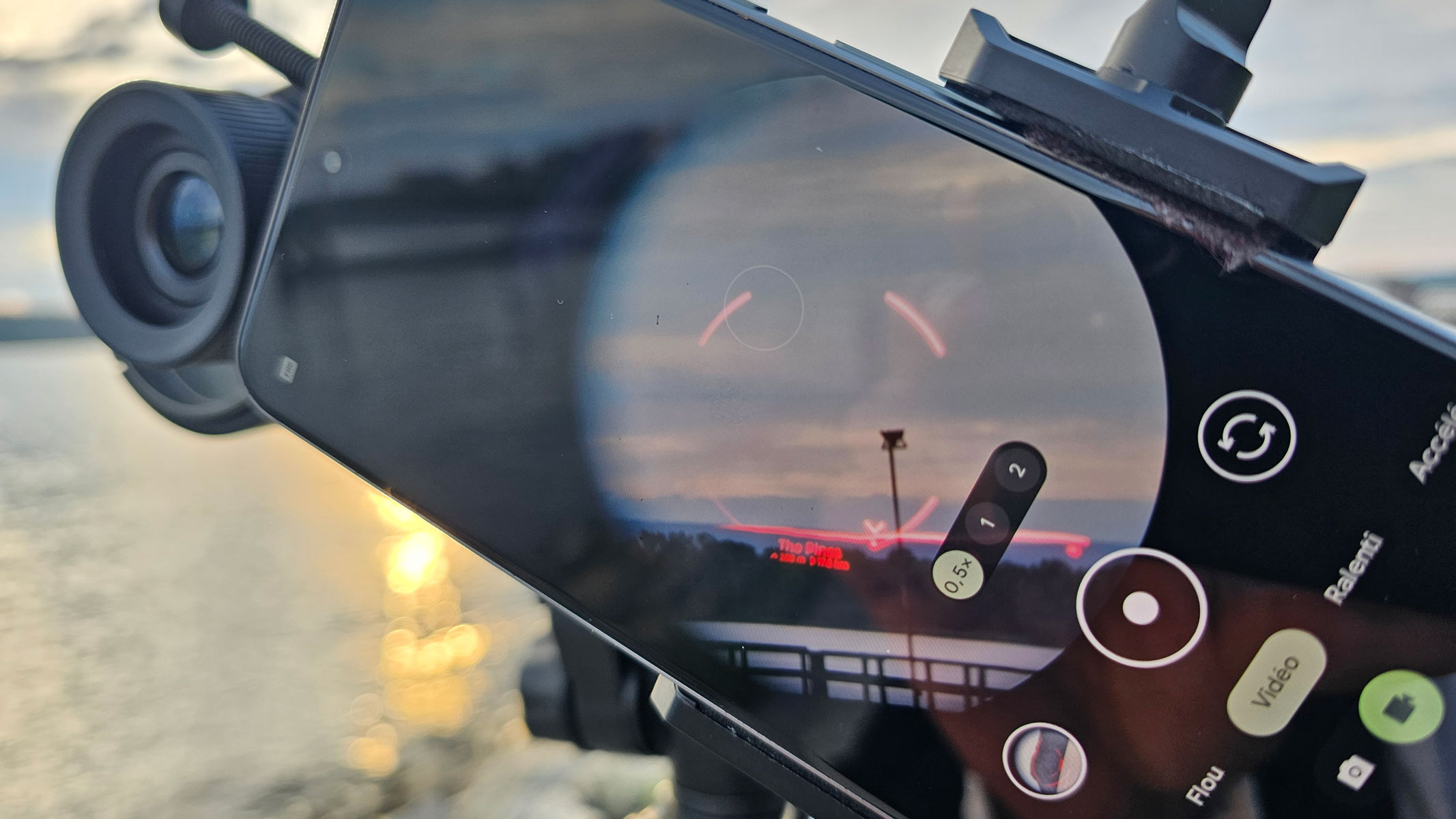 A smartphone showing the view through Unistellar Envision binoculars with a red AR overlay of a mountain.