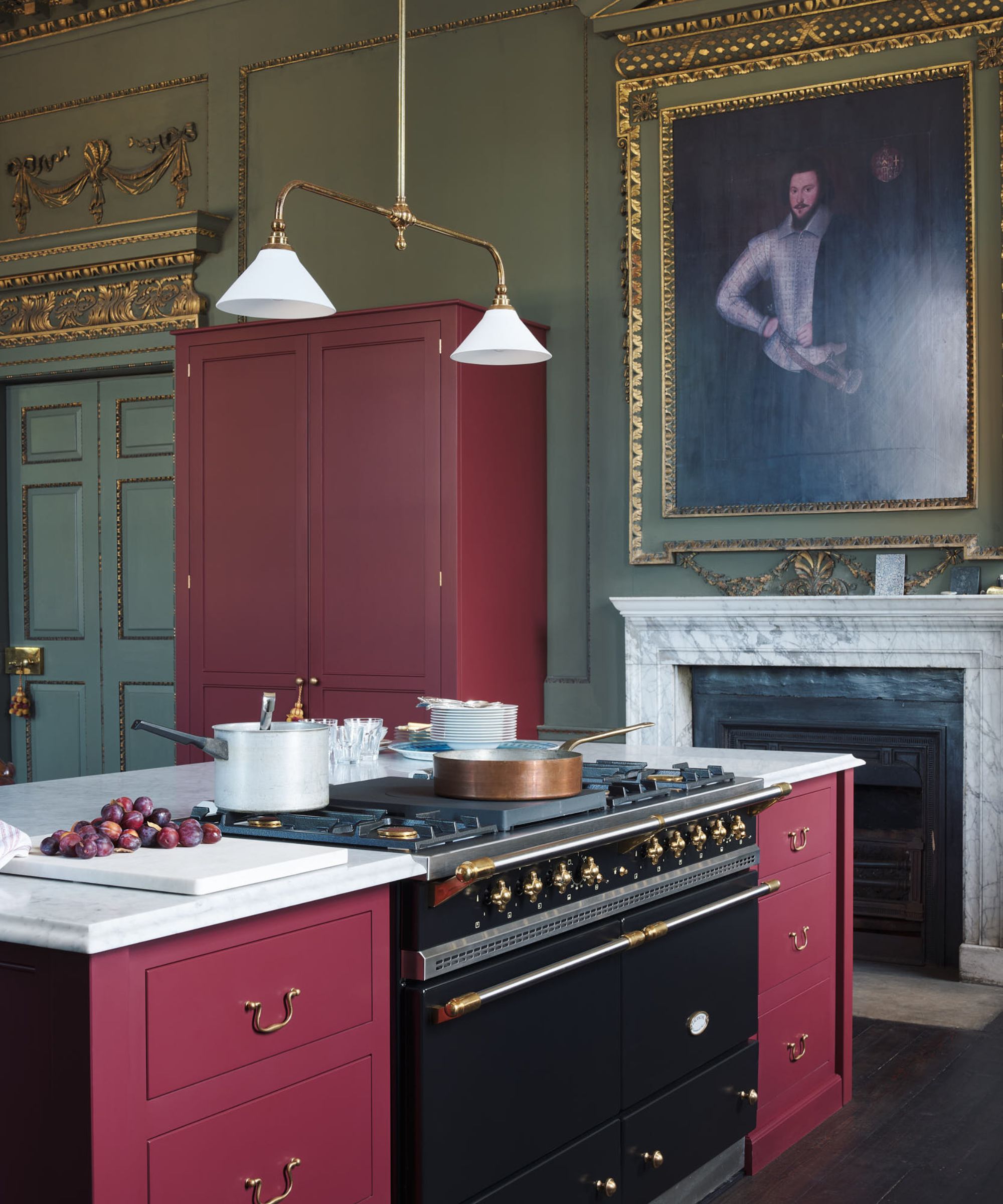 A stately eat-in kitchen with green walls, red cabinets and marble countertops