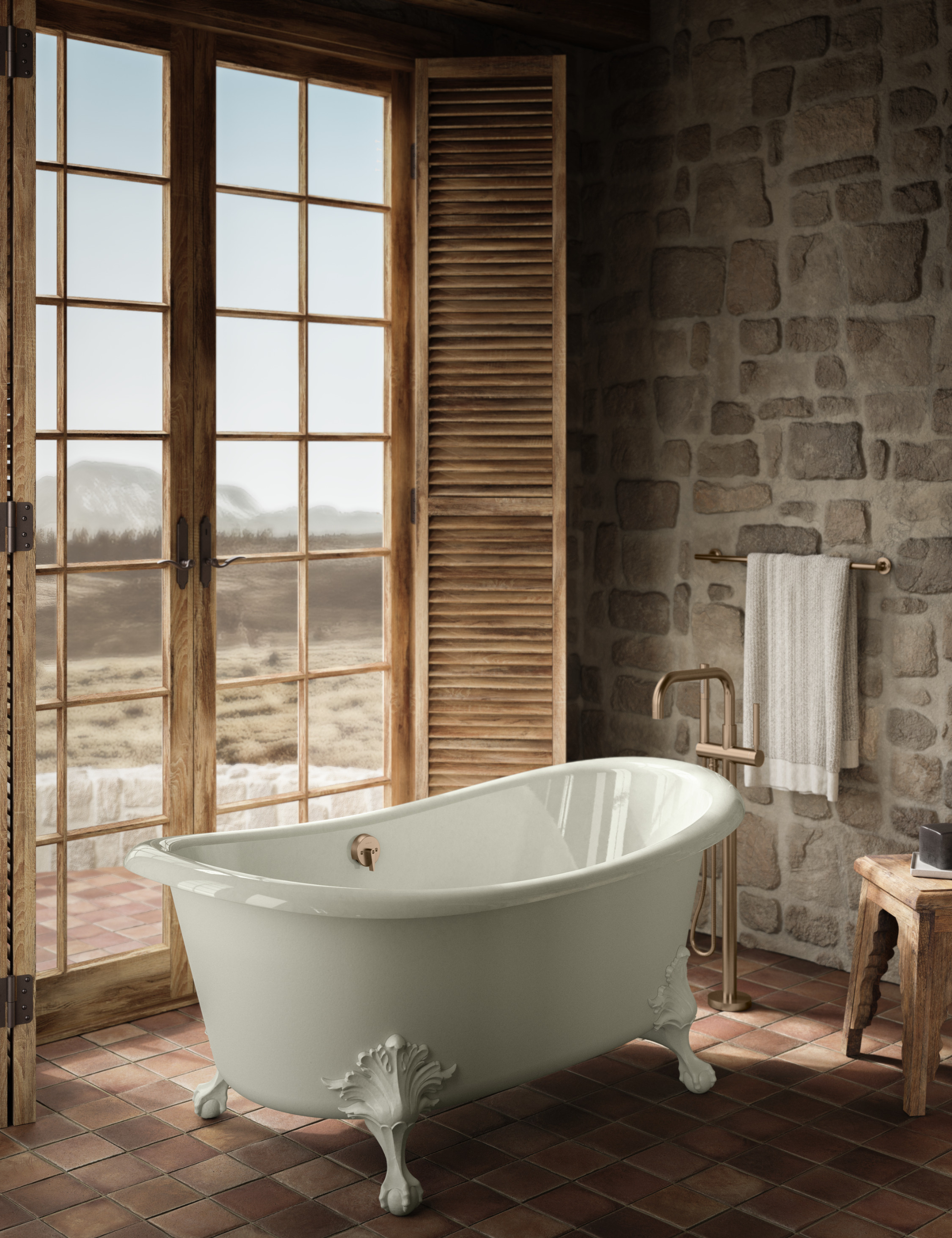 Kohler's Artifacts freestanding bathtub is pictured with ornate legs in a rustic bathroom overlooking a desert scene