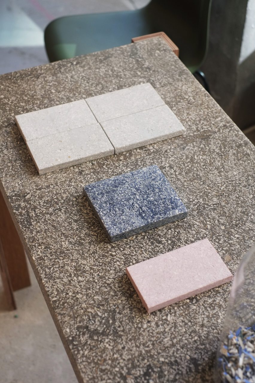 Photo of samples of cupsan material in cream-colored, denim blue and light pink, rest on a Cupsan table plate of colored espresso brown