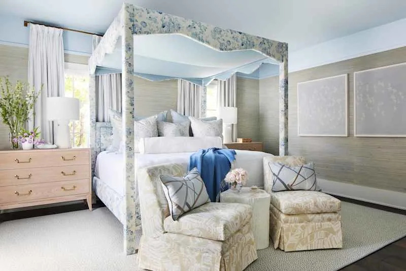 Brightly decorated bedroom with a floral four-poster bed, soft pillows and bright accent chairs.