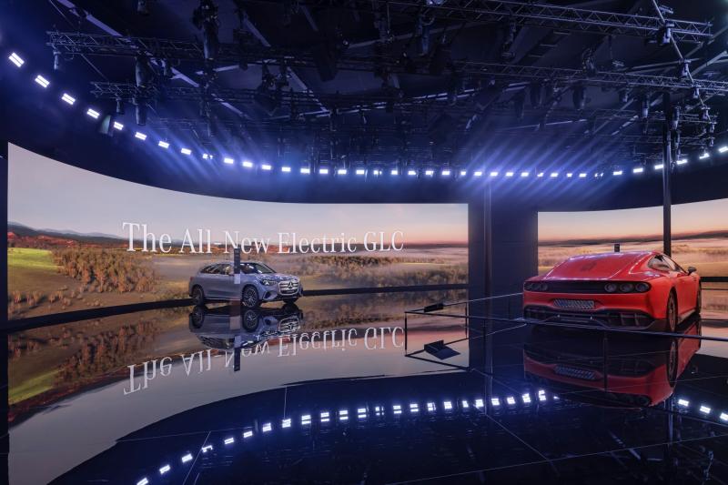 Two Mercades cars, red and silver, in a showroom lit by blue lights.