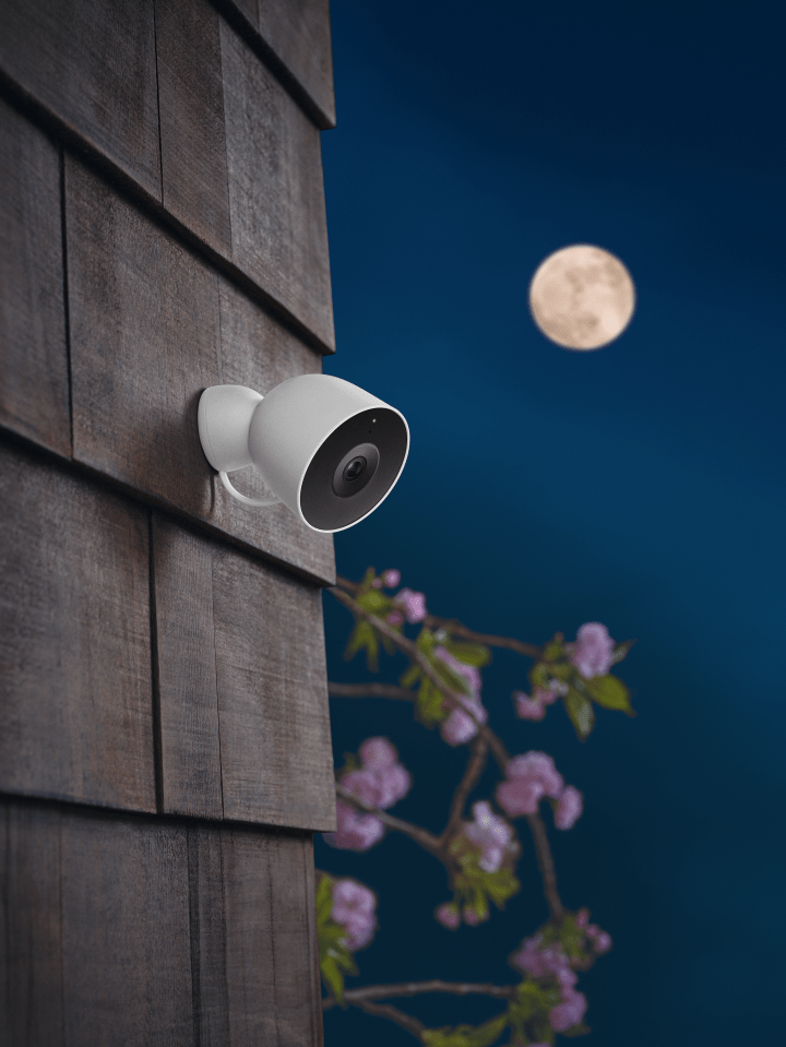 Monitoring camera on the side of a building under full moon.