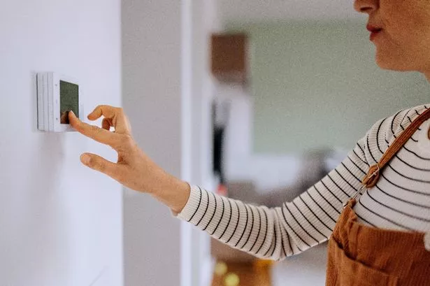 Woman who sets the temperature on smart thermostat at home