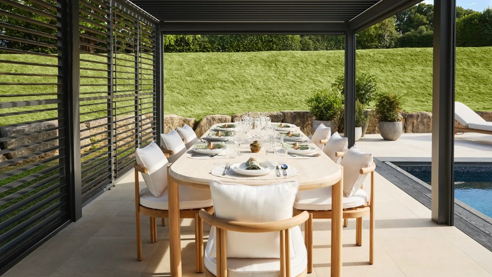 Outdoor dining area with a long table for 10 people under a pergola.