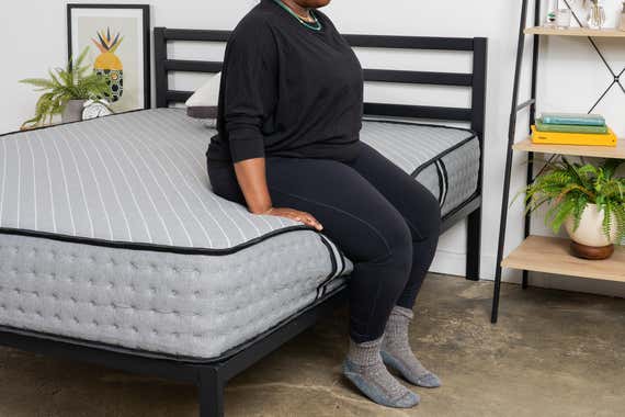 Someone who sits on the edge of a Siena Hybrid Premier mattress.