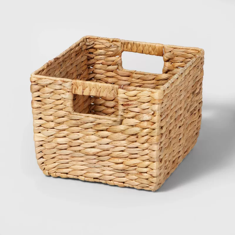 A small, cube-shaped storage basket with cut-out handles.