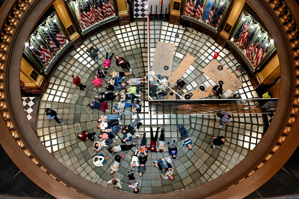 A group from Central Elementary School in Davison lay on the glass floor as a team works on part of the floor restoration at the Michigan State Capitol on Friday, Oct. 10, 2025, in Lansing.