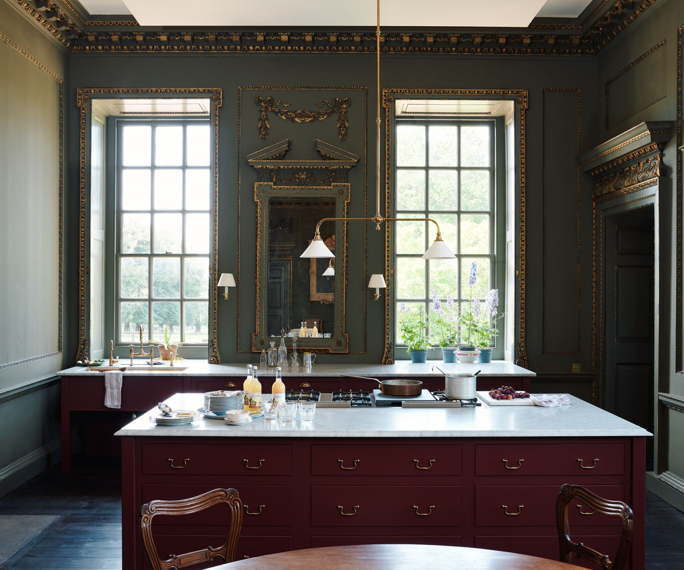 A stately eat-in kitchen with green walls, red cabinets and marble countertops