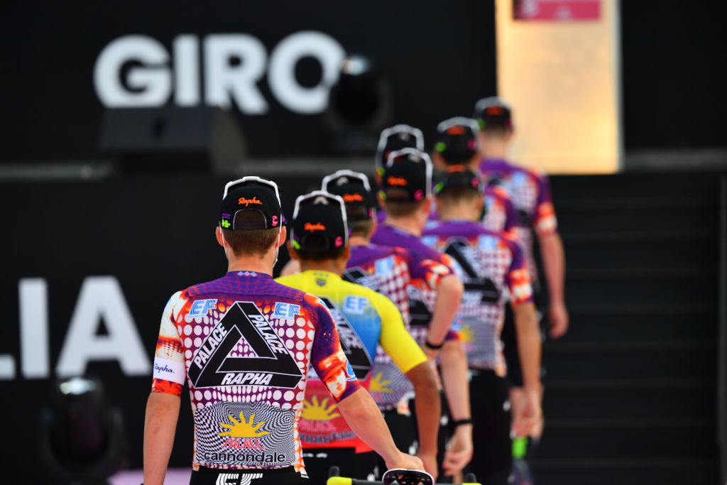 Men line up with bicycles for a team presentation