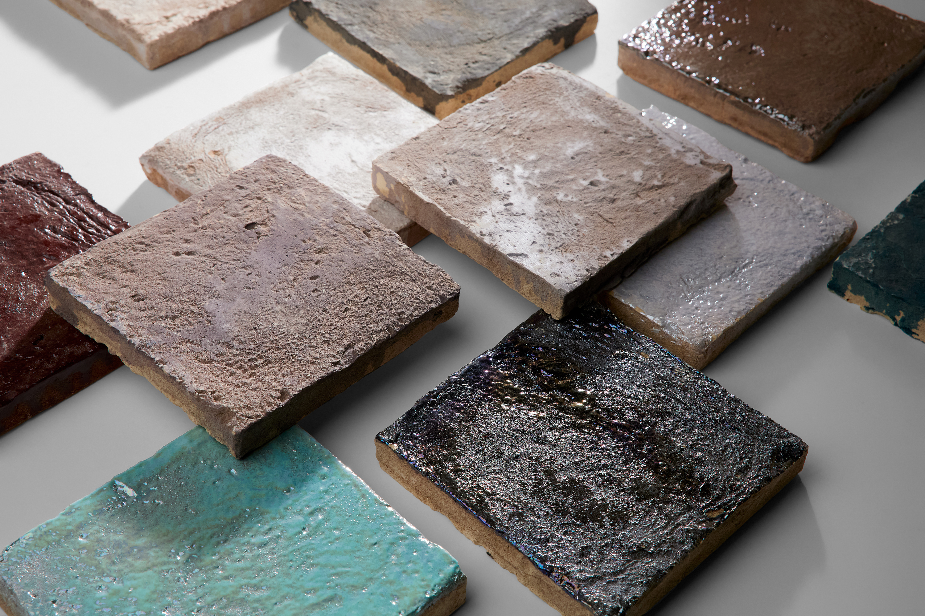 Square tiles in various earth tones are laid on a white surface.